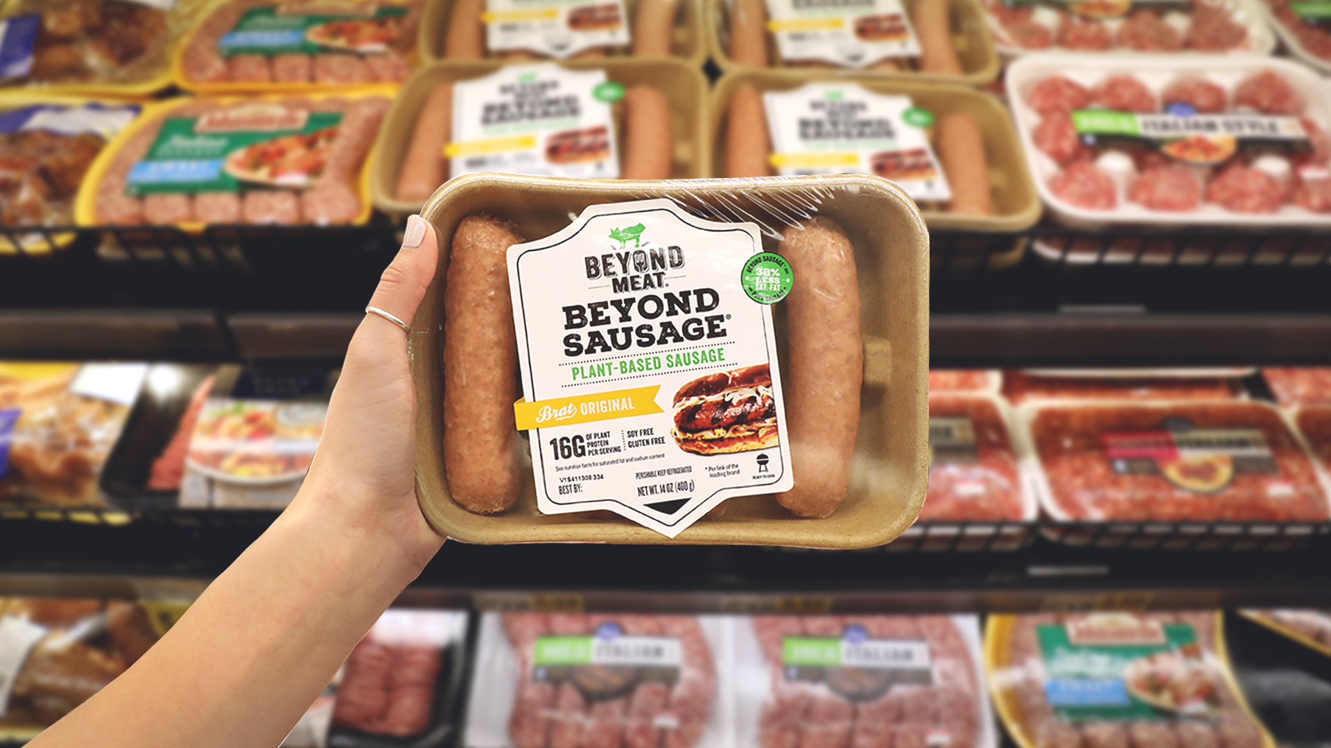 A hand holding up a package of Beyond Sausage.