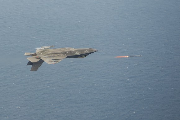 A F-35 flying out over water performing a missile firing test.