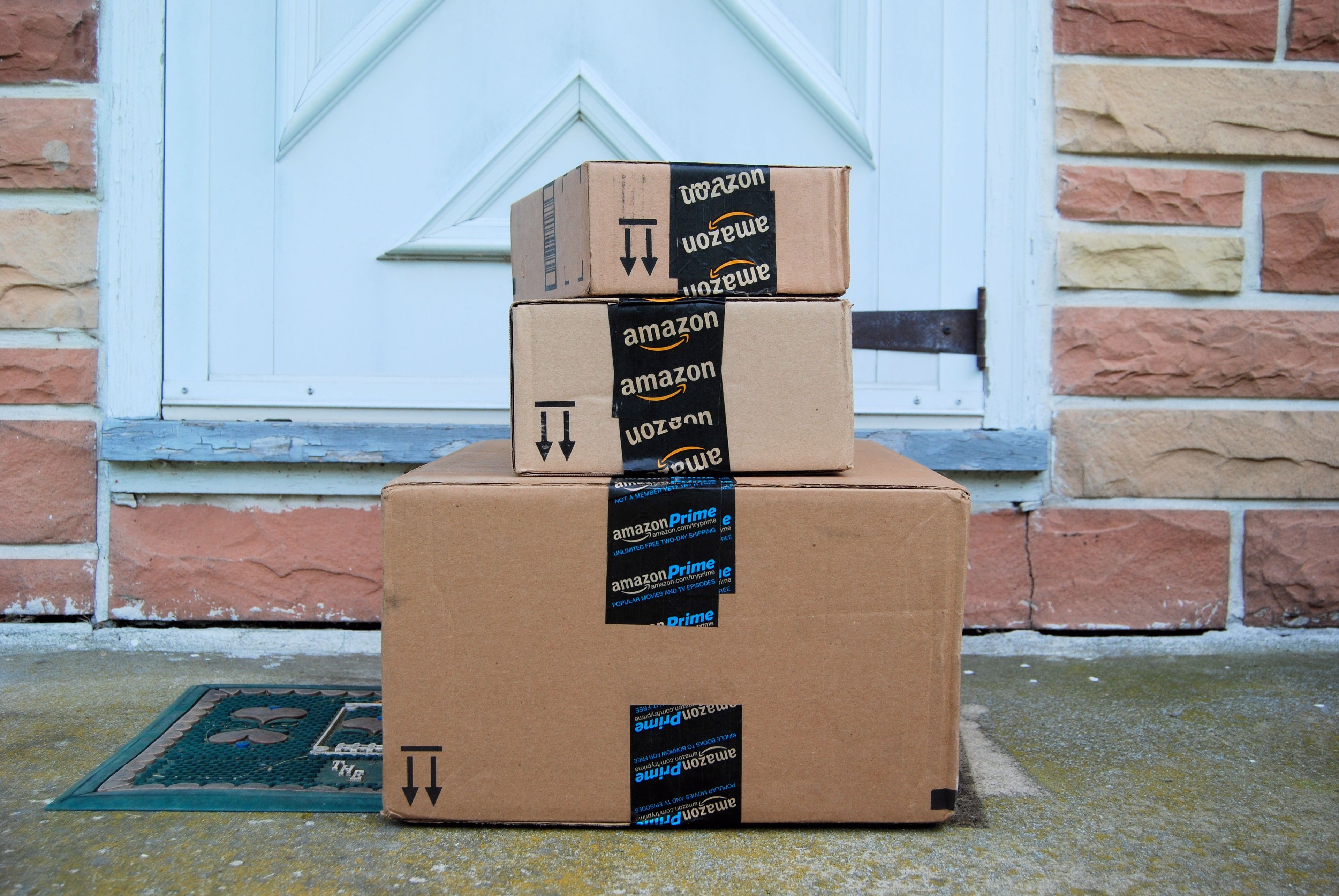 A stack of Amazon boxes outside a door.
