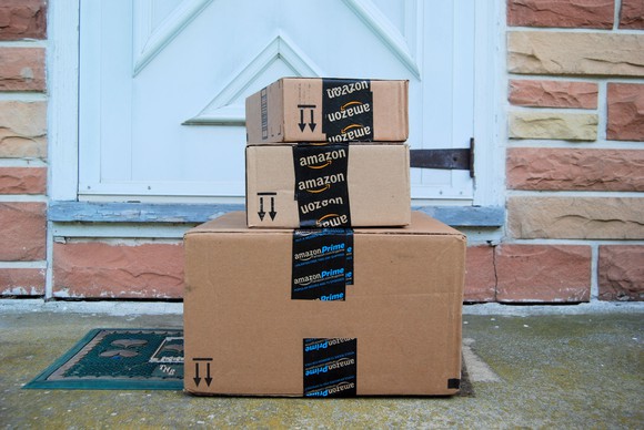 A stack of Amazon boxes outside a door.
