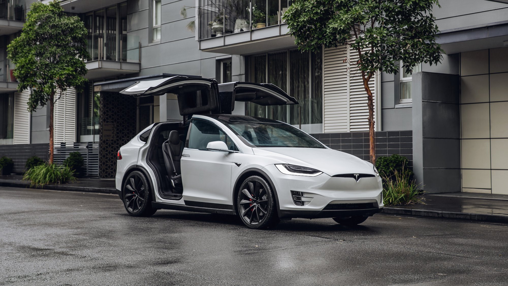 A white Model X with its falcon wing doors open