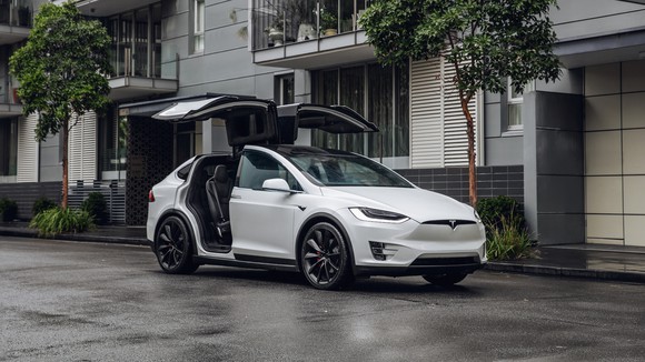 A white Model X with its falcon wing doors open