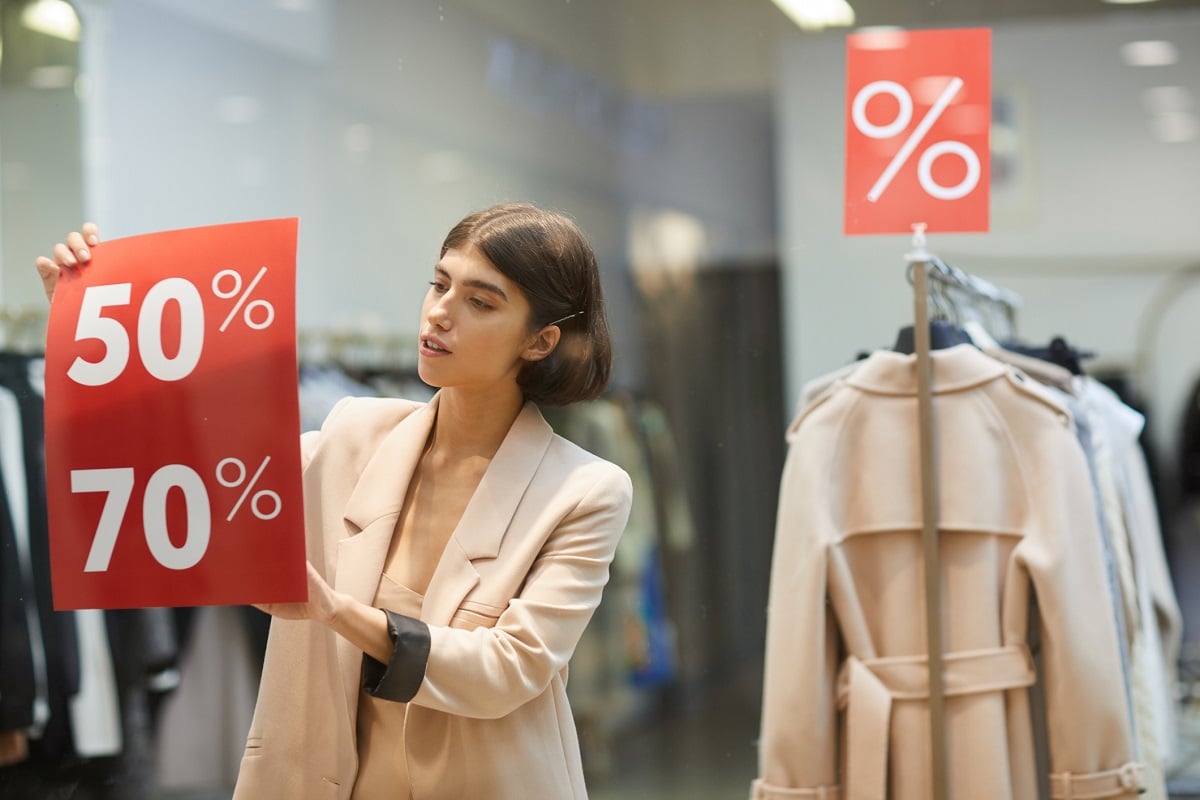 Woman putting Discount signs in a shop window