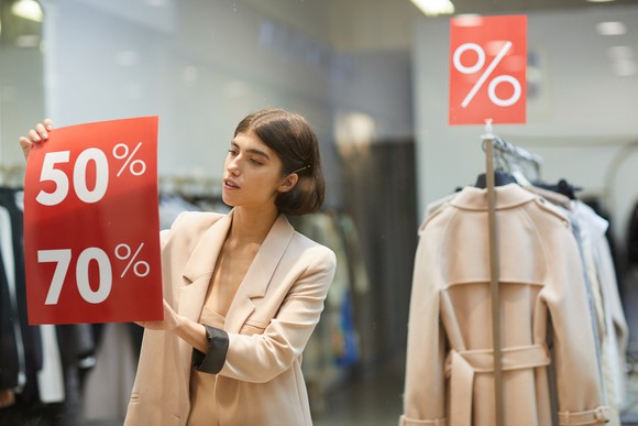 Woman putting Discount signs in a shop window
