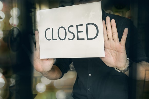 A person posting a sign with the word closed on it.