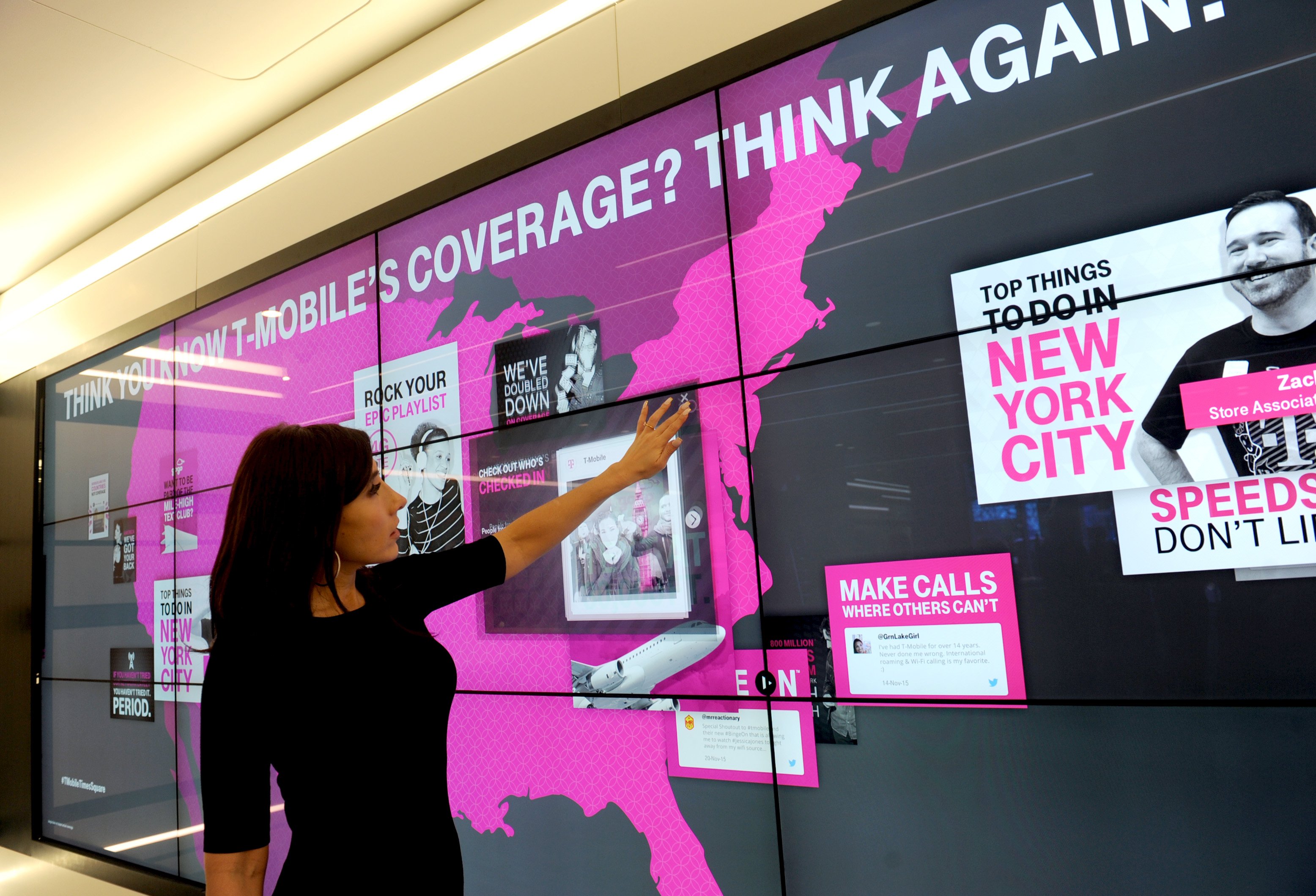 A woman points at a display in a T-Mobile store.