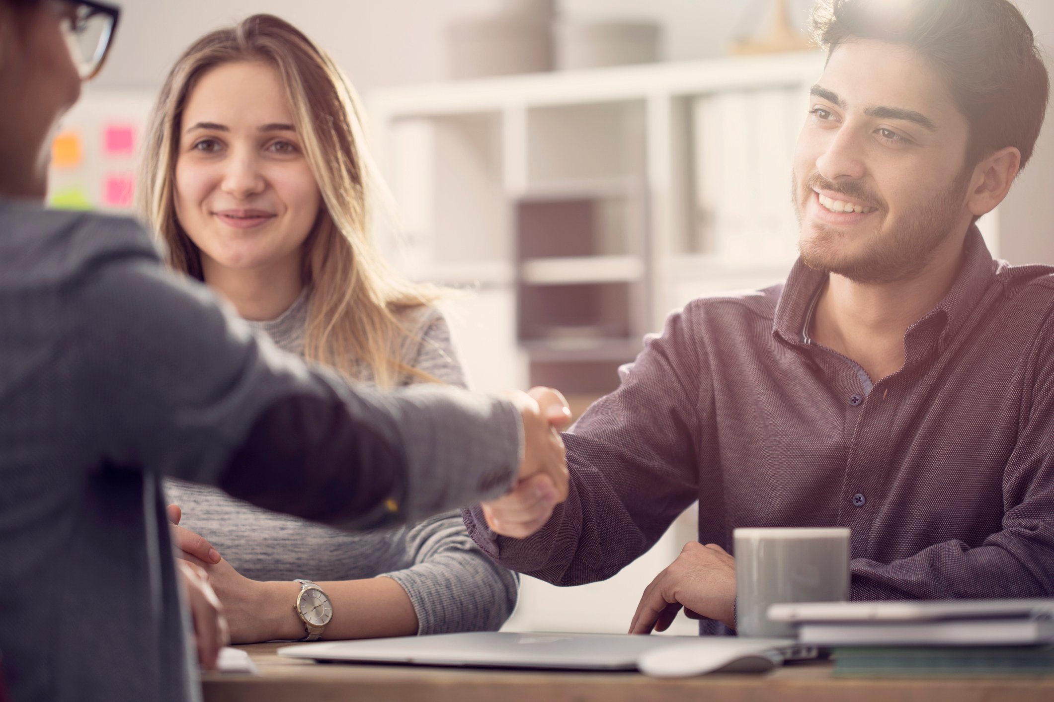 Couple shaking hands with man in suit