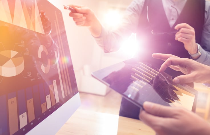Two people evaluating charts on a screen.