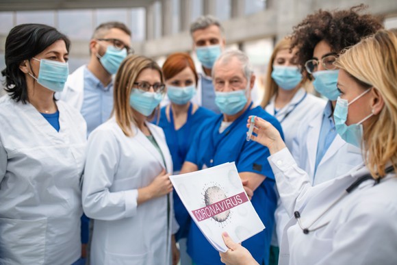 A group of doctors discuss the coronavirus outbreak outside a hospital.