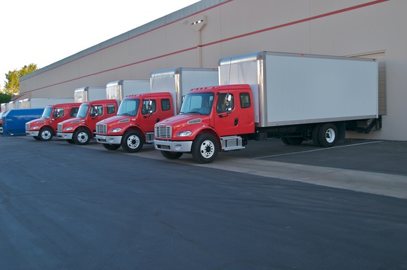 Semi-trucks backed up to loading bays at a fulfillment warehouse.