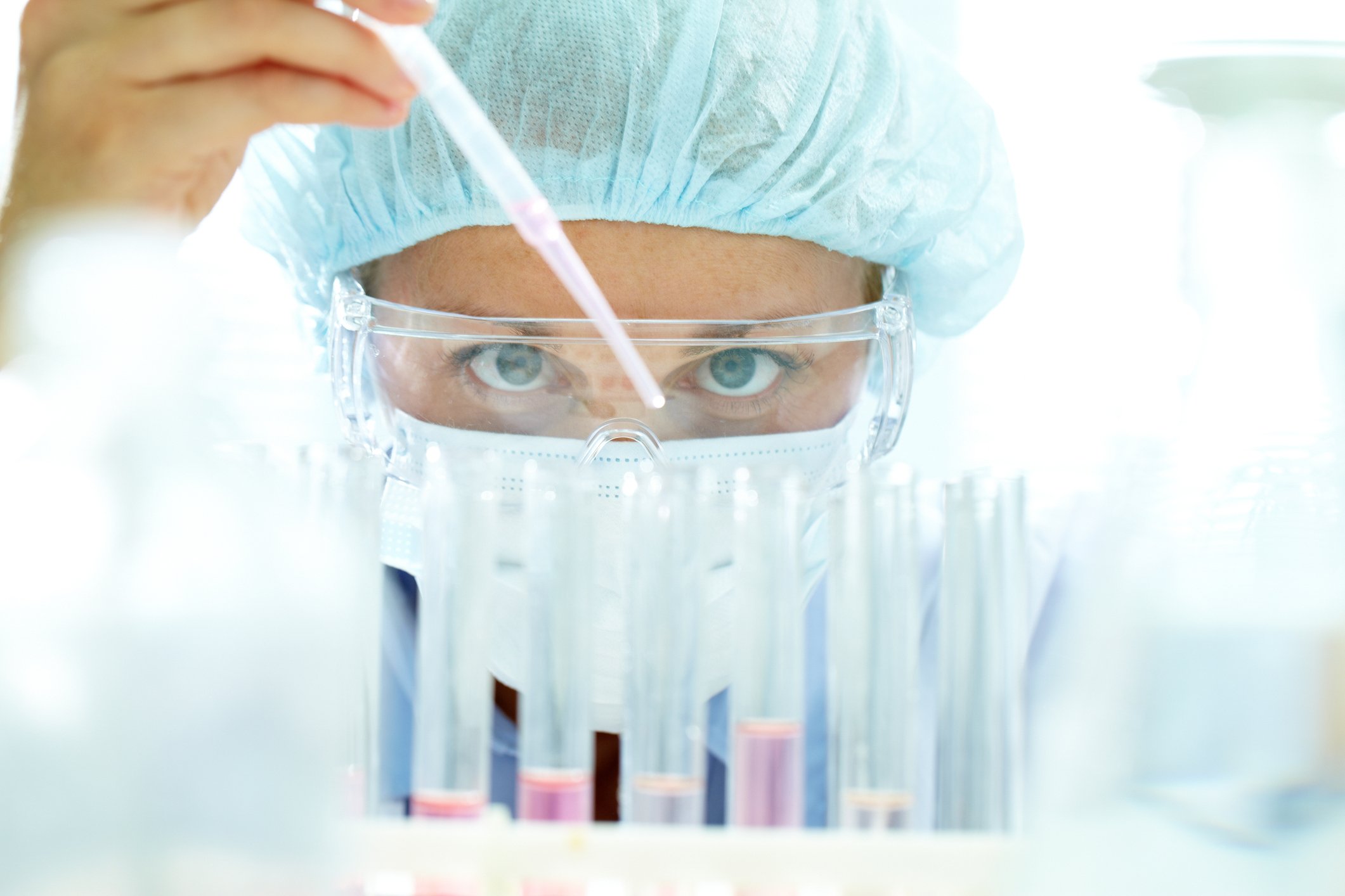 A biotech lab researcher using a dropper to place liquid into test tubes.