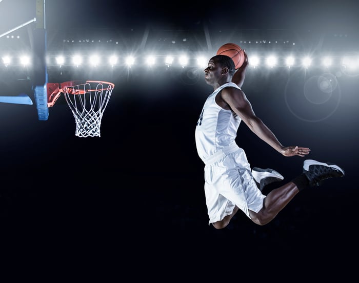 A basketball player jumps to make a slam dunk.
