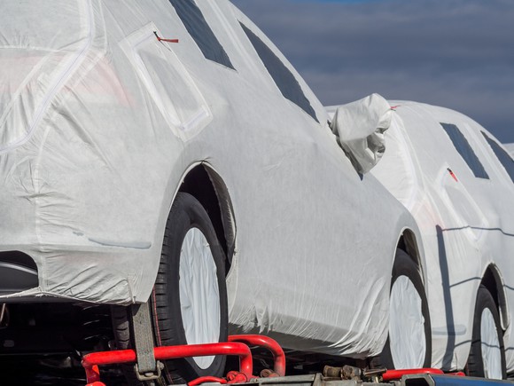 Produced cars covered in white, waiting to move from manufacturer
