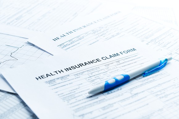 Health insurance claim forms laid on a desk with a pen on top.