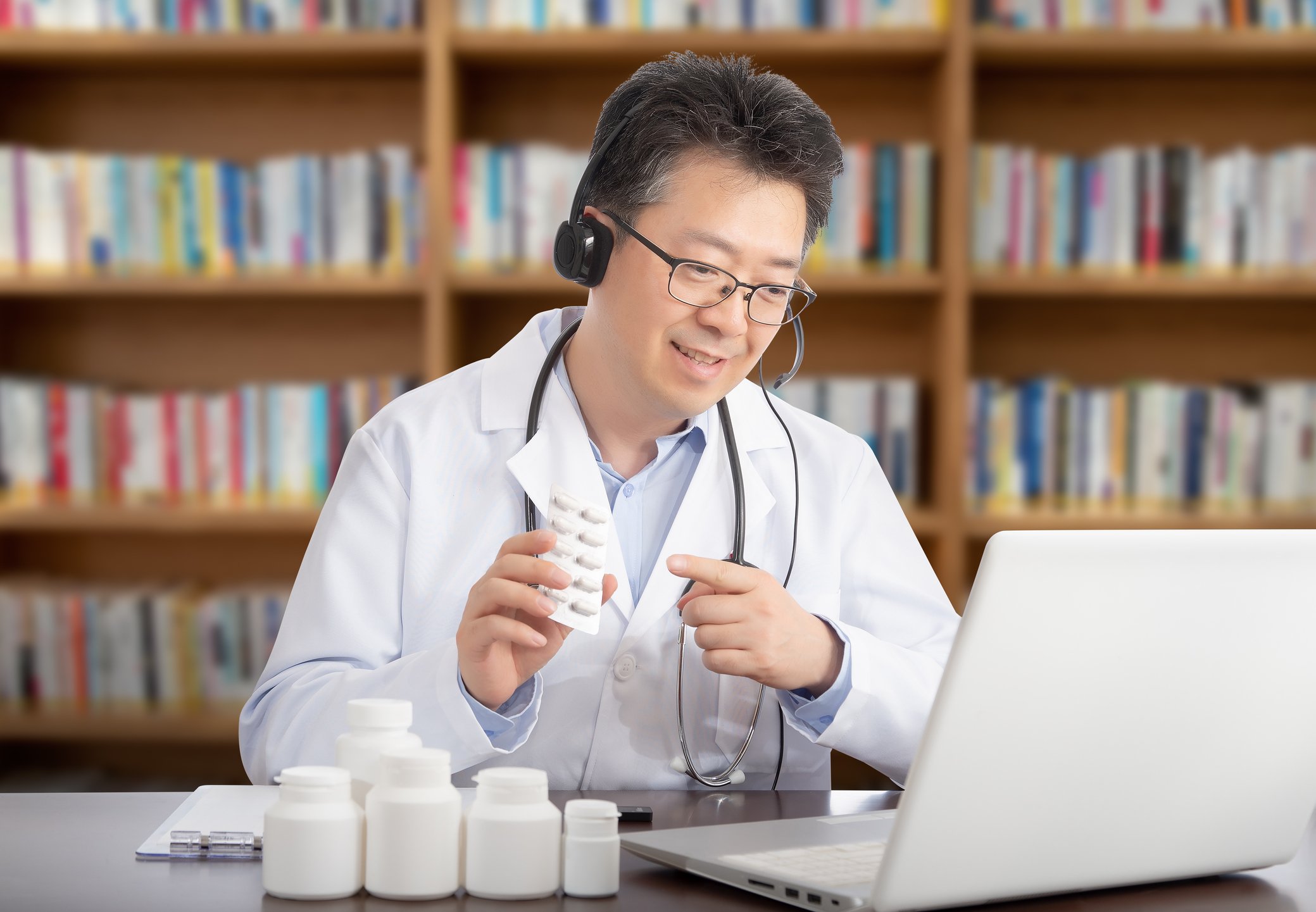 A doctor providing a medical consultation online via his laptop.