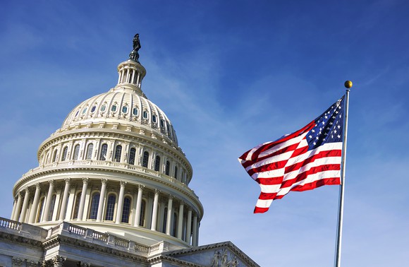 A picture of Capital Hill with an American flag flying on a clear sky.