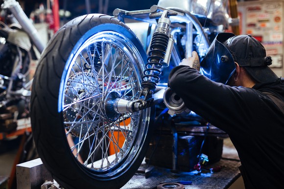 Welder working on motorcycle on shop table