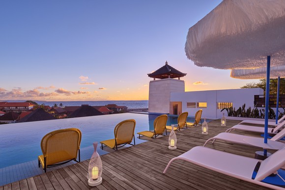 A hotel pool in Bali with empty chairs.