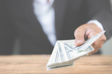 Man in suit handing over a wad of cash