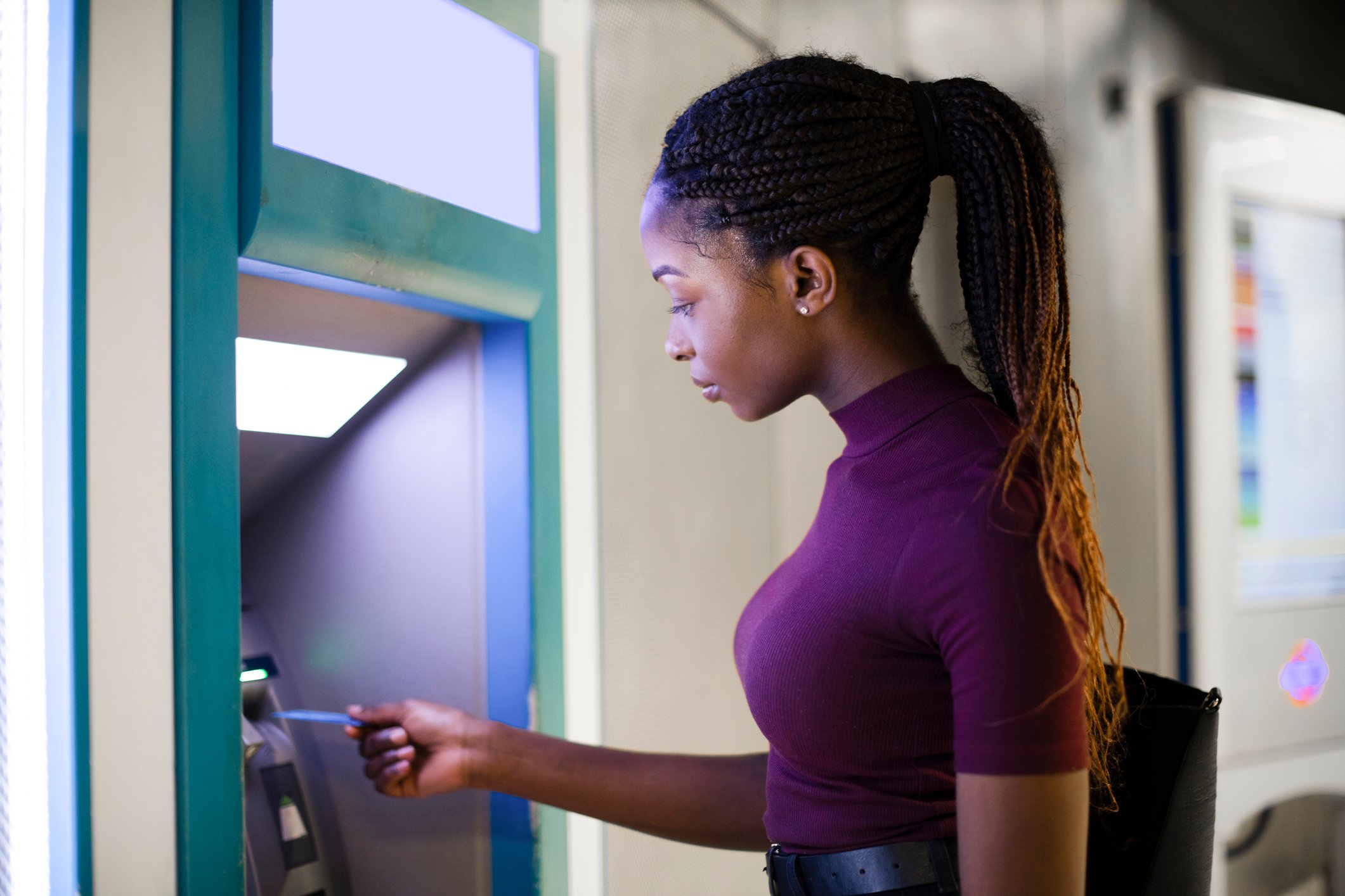 A woman putting a card into an ATM.