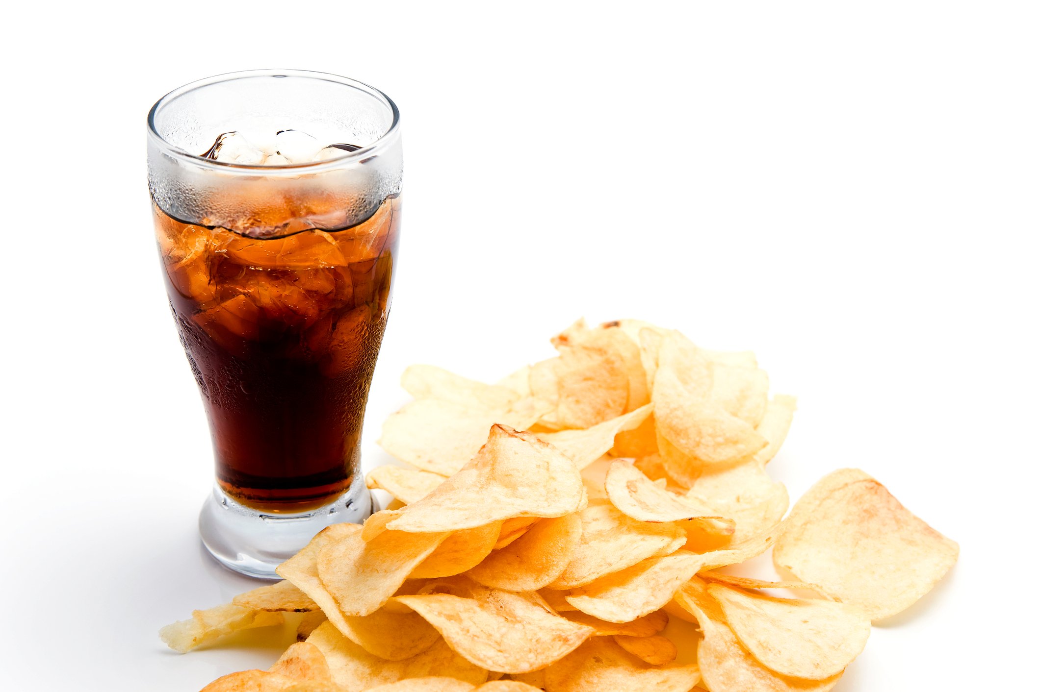 Glass filled with ice and cola next to some potato chips