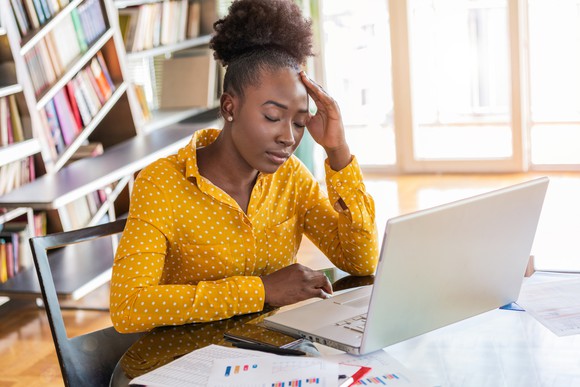 Woman in front of laptop holding head