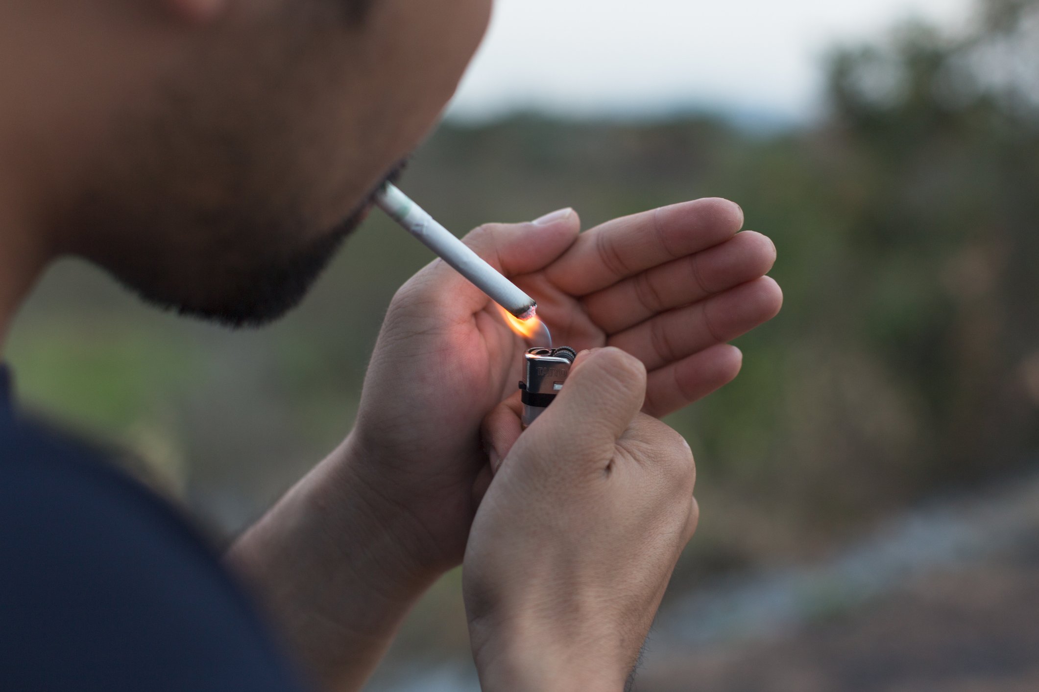 A man lighting a cigarette.