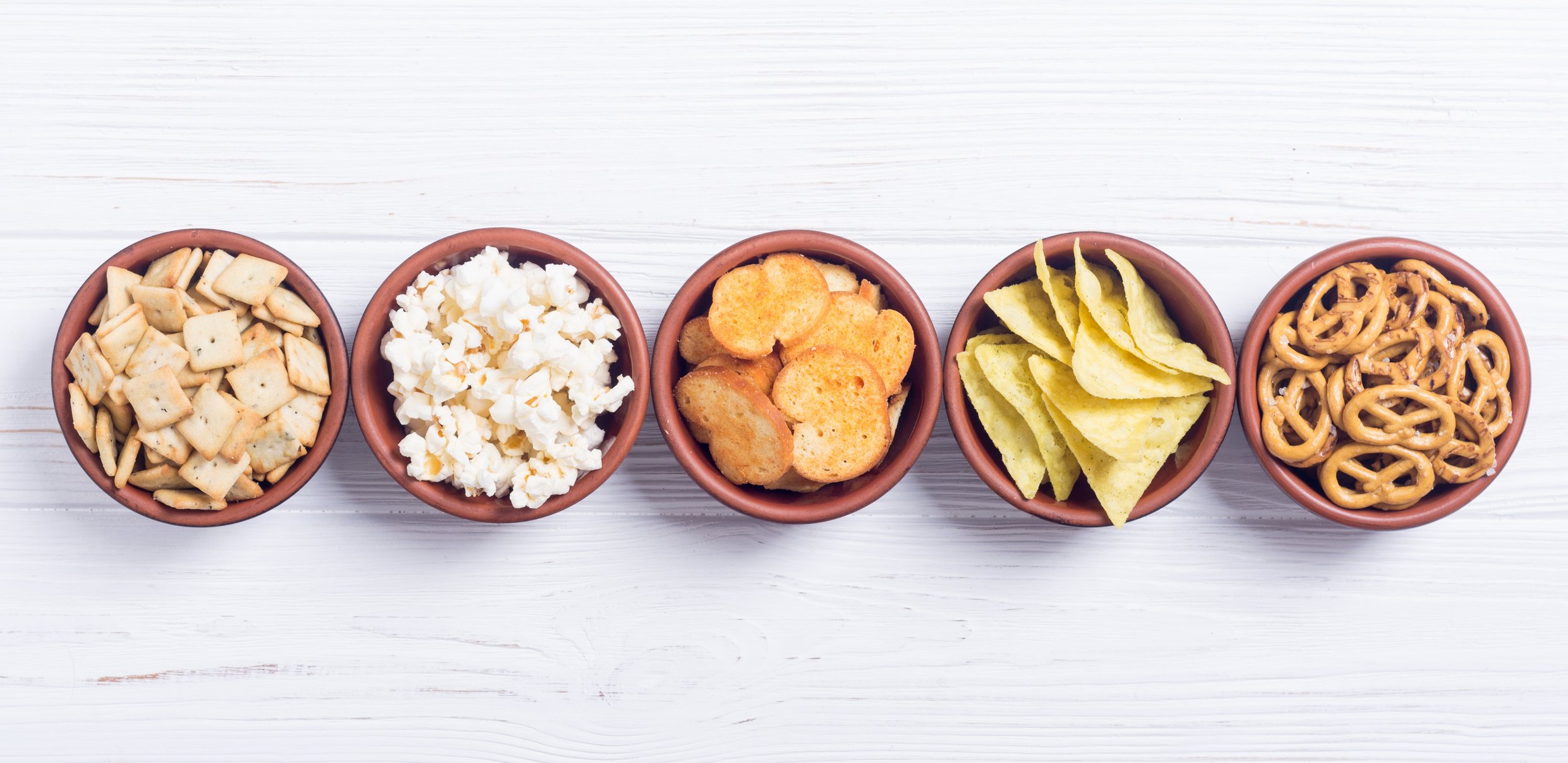 Bowls of crackers, pretzels, potato chips, and popcorn.