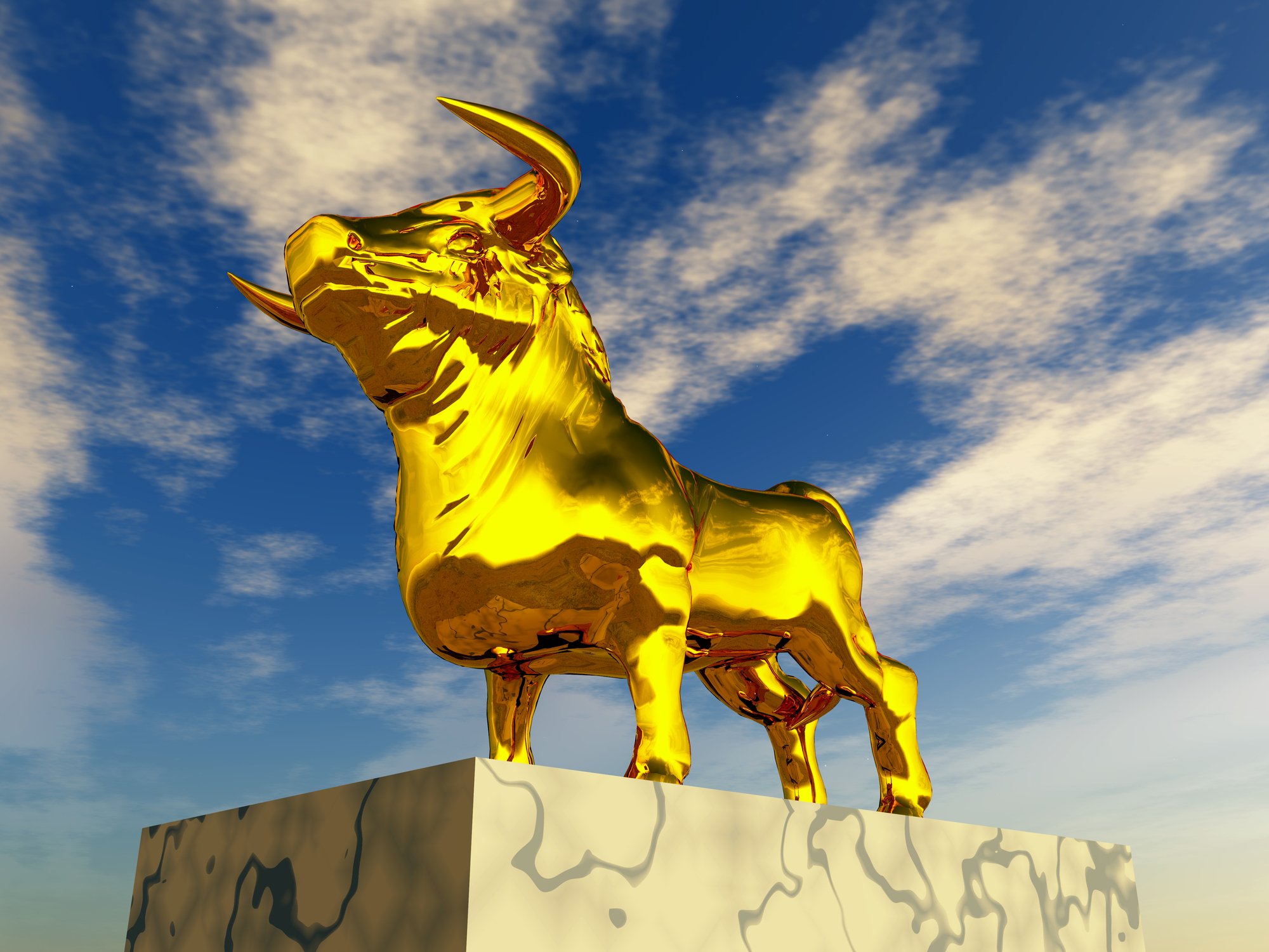A golden statue of a bull, seen against the backdrop of partly cloudy skies.
