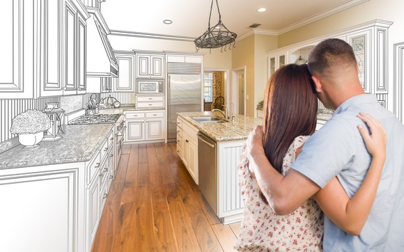 Couple staring at their kitchen covered in a schematic of their future kitchen.