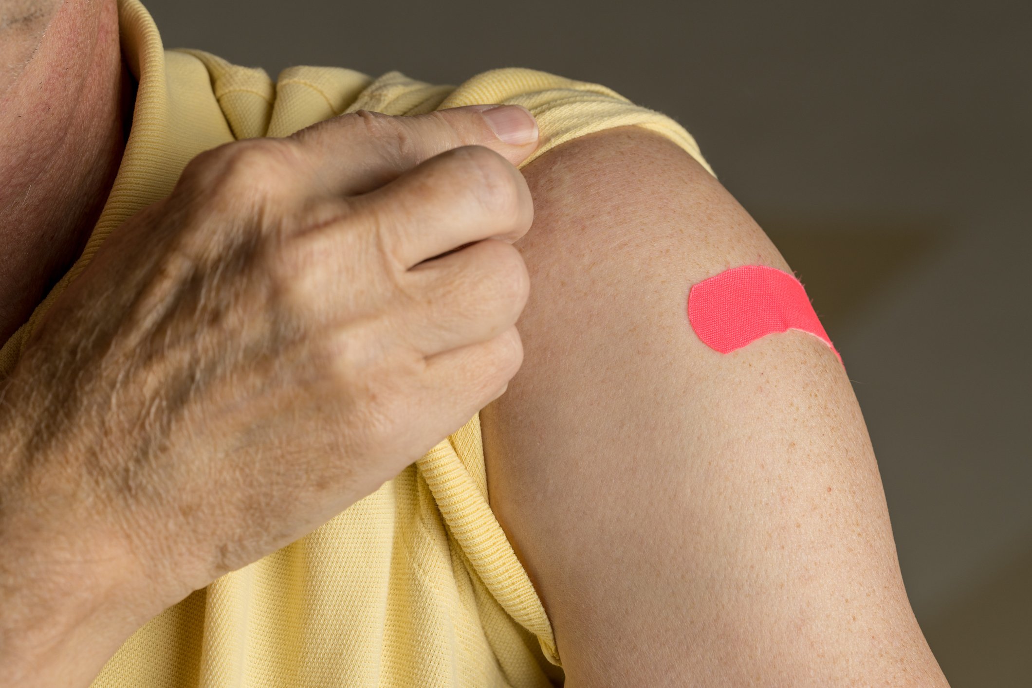 A senior man holding up his sleeve after a flu shot.