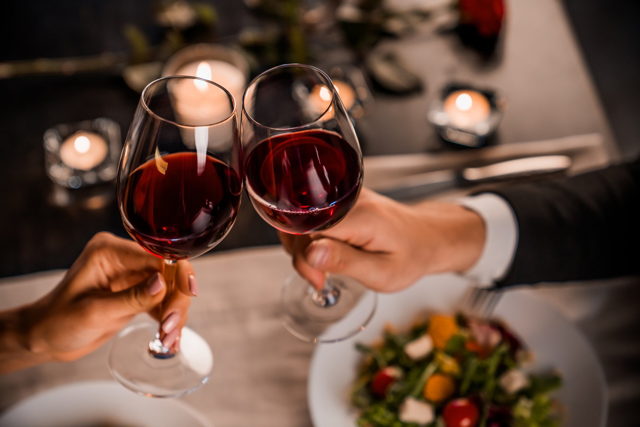 Two people toasting wine glasses at a restaurant. 