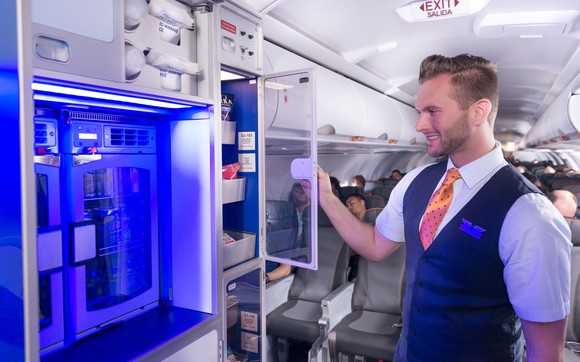 A JetBlue flight attendant checking on the snacks and chilled beverages with passengers sitting in the cabin.