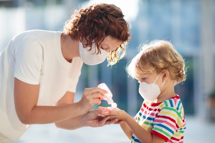 Mom putting hand sanitizer on her child. 