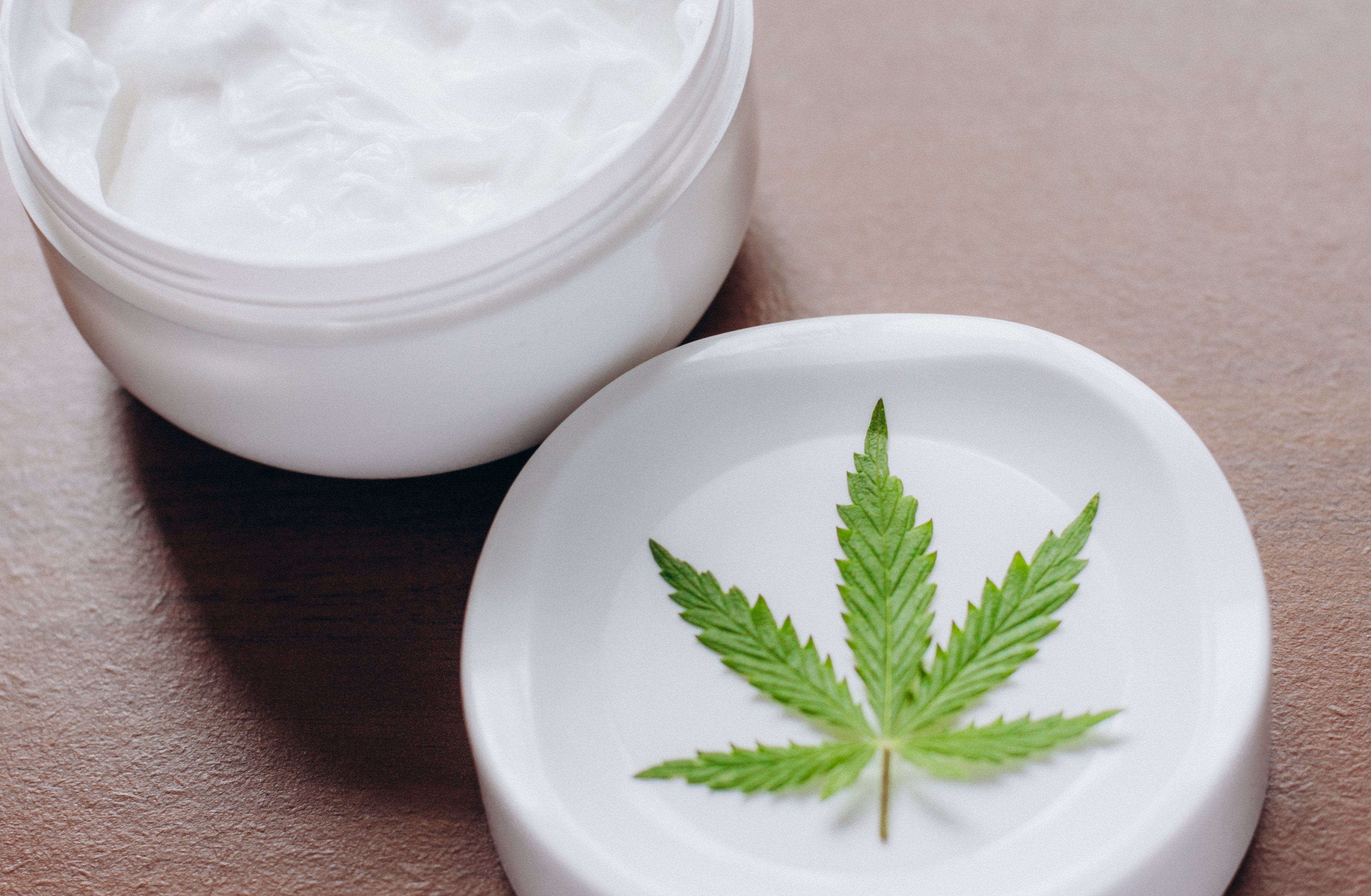 Jar of cream with cannabis leaf.