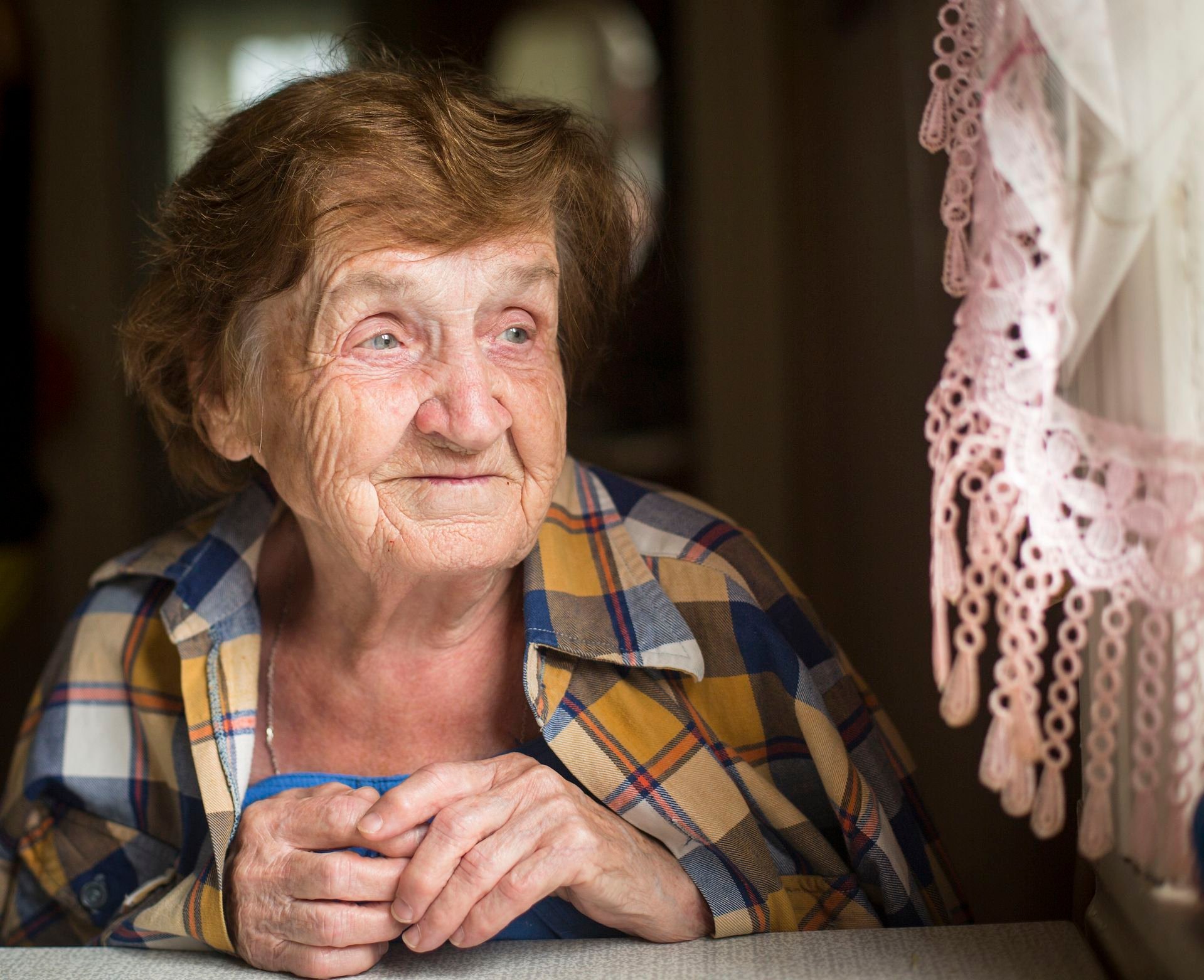Older woman looking out window.