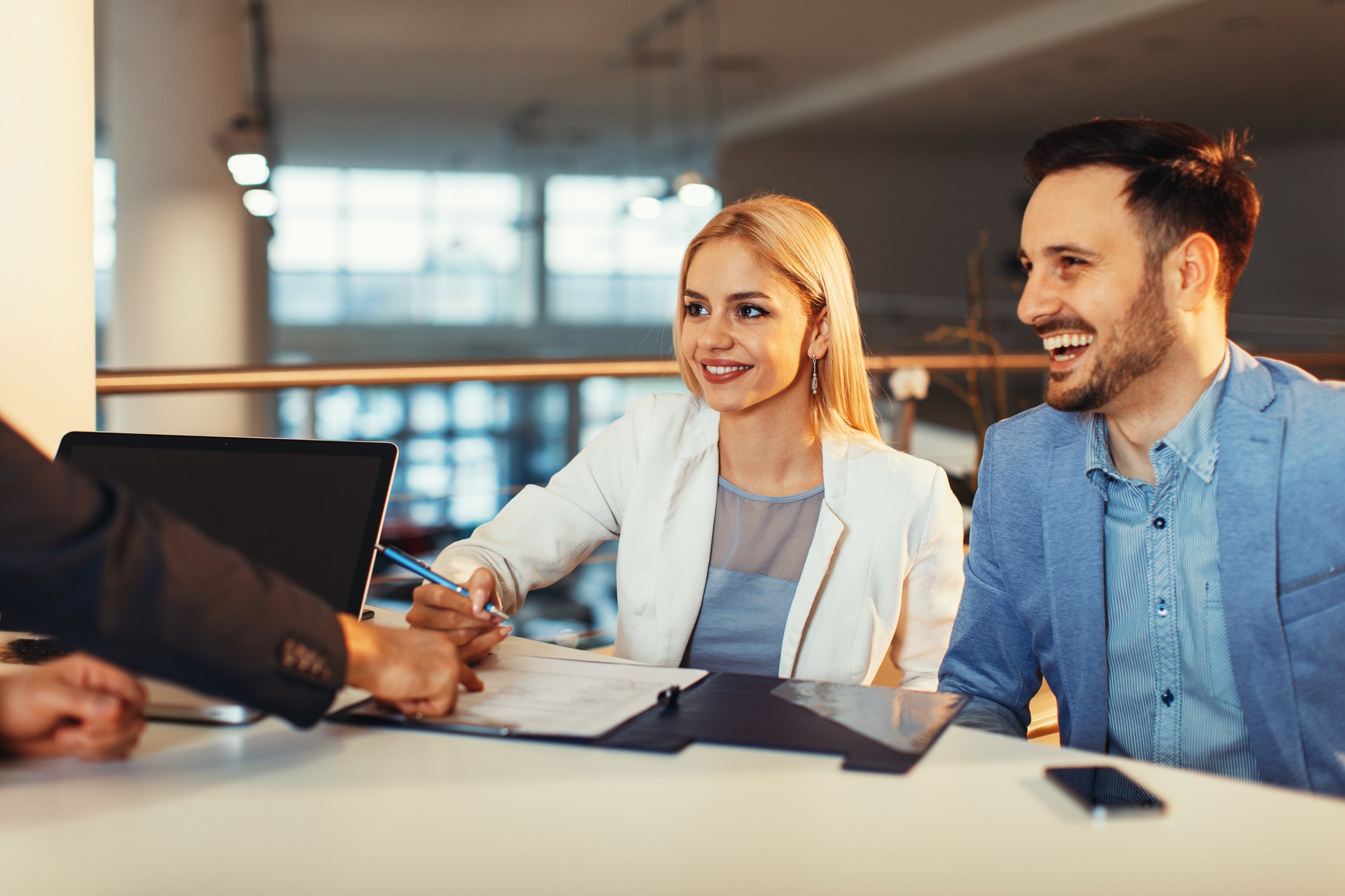 Couple at a desk signing paperwork.