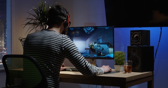 Video game player at desk, playing a game.