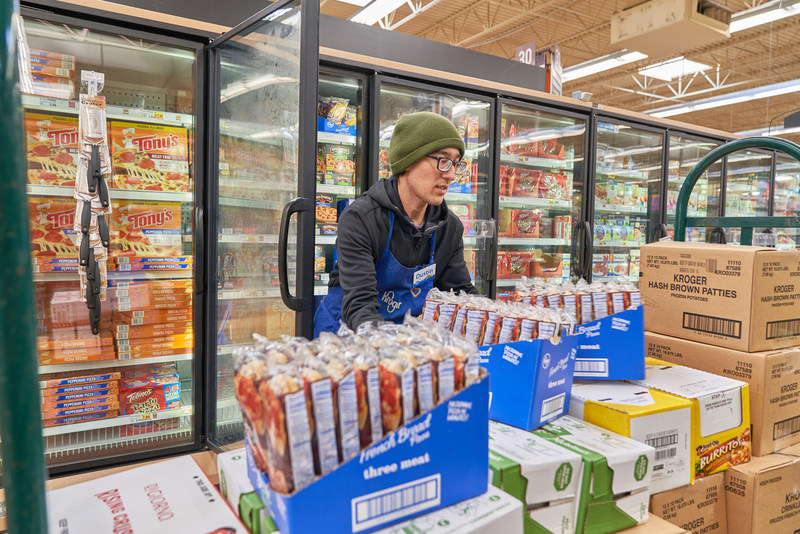 A Kroger worker stocks a freezer.