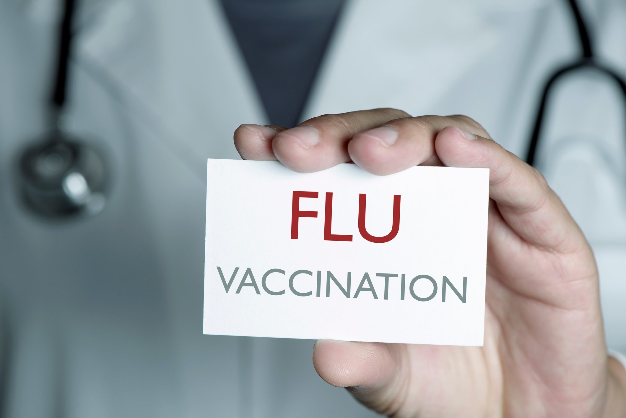 A doctor holding a card that says 'flu vaccination.'