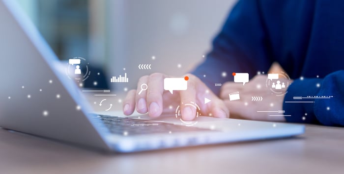 A man's fingers touching the keyboard on a laptop.