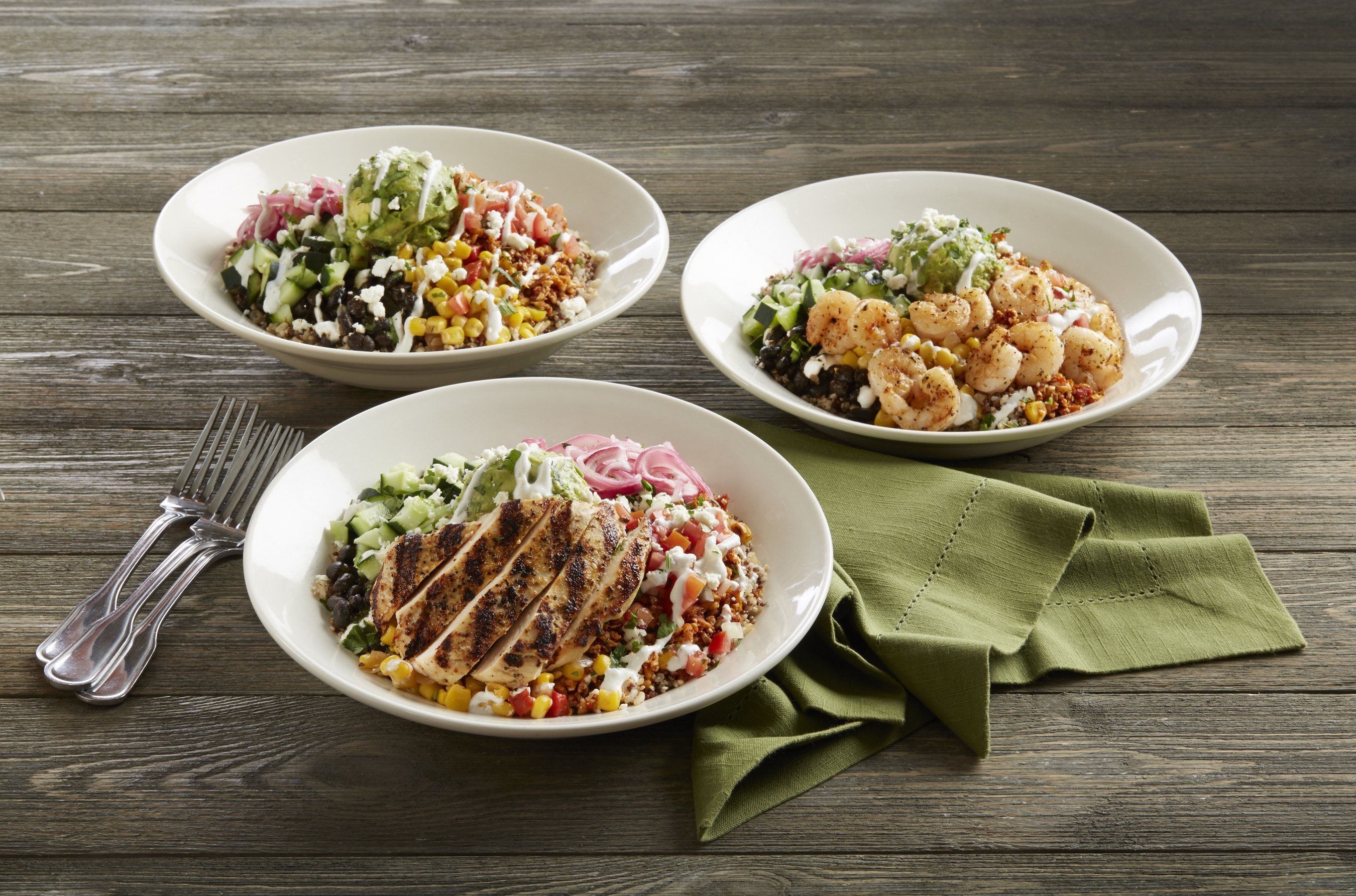 bowls holding food items from BJs Restaurants menu sit on a table with a napkin and forks