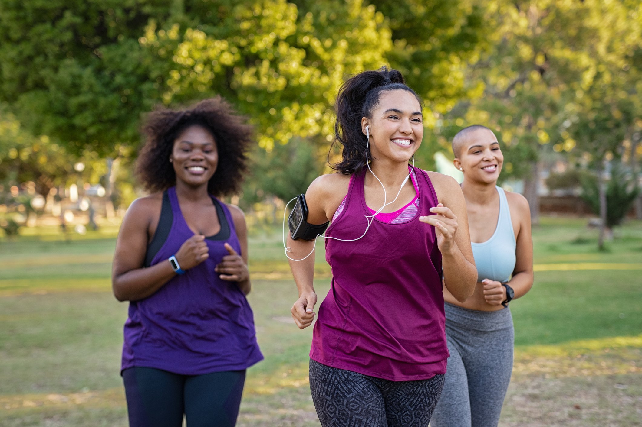 Three women are smiling while they are jogging.