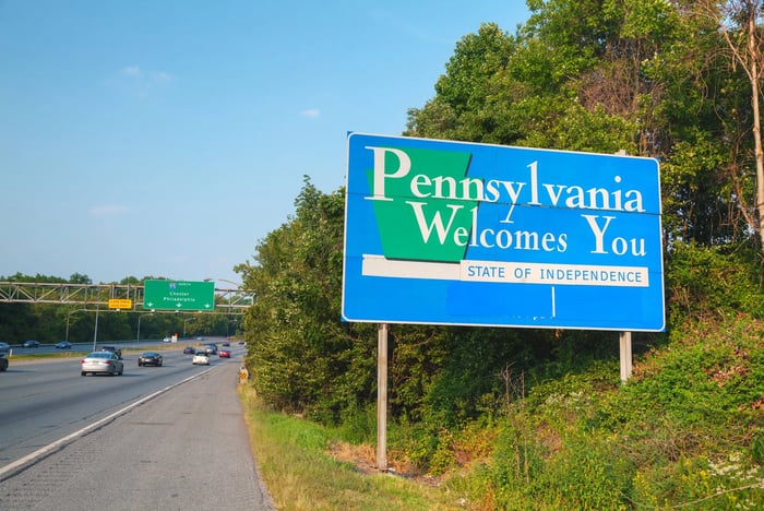 Road sign saying Pennsylvania Welcomes You by side of interstate.