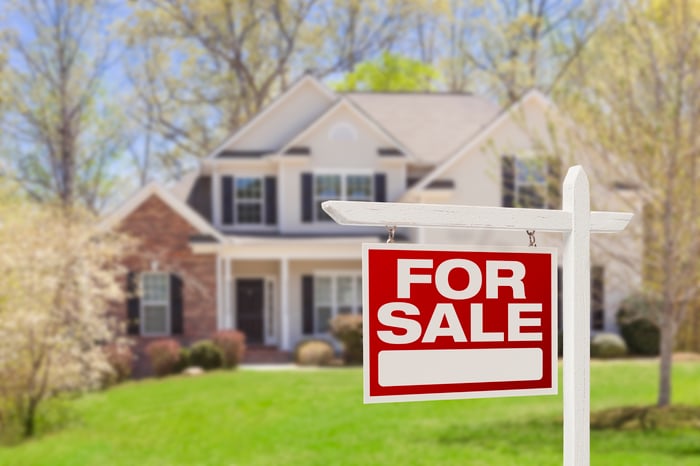 House with For Sale sign in front yard. 