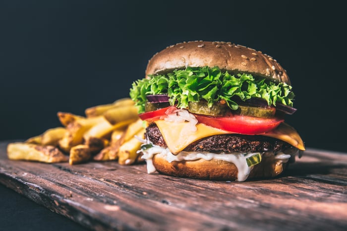 An artisan hamburger and steak fries on a wooden table.