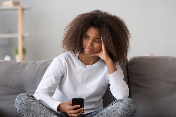 Young woman sitting at home with a phone in her hand. 