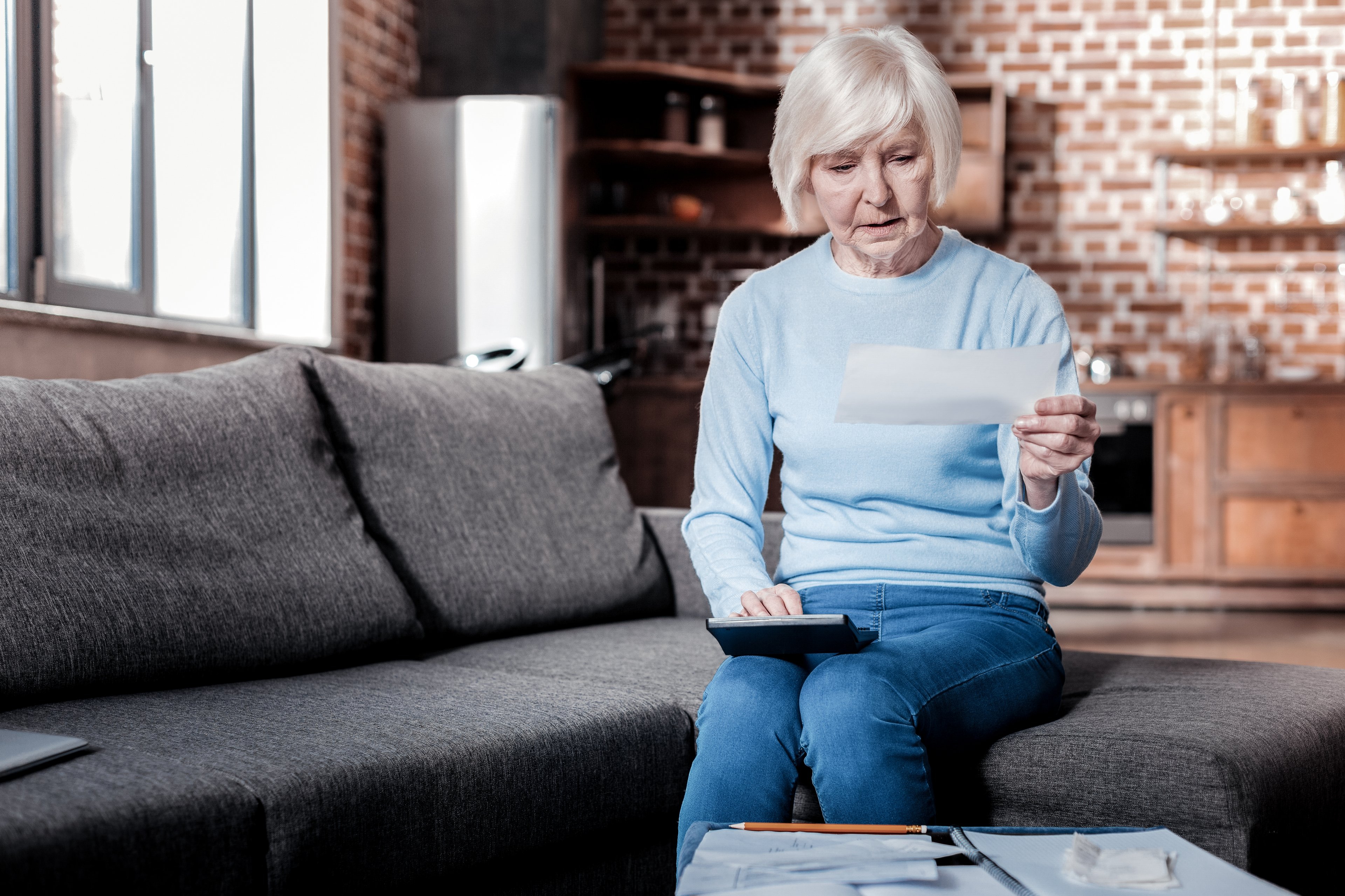 Older woman looking at check and appearing worried.