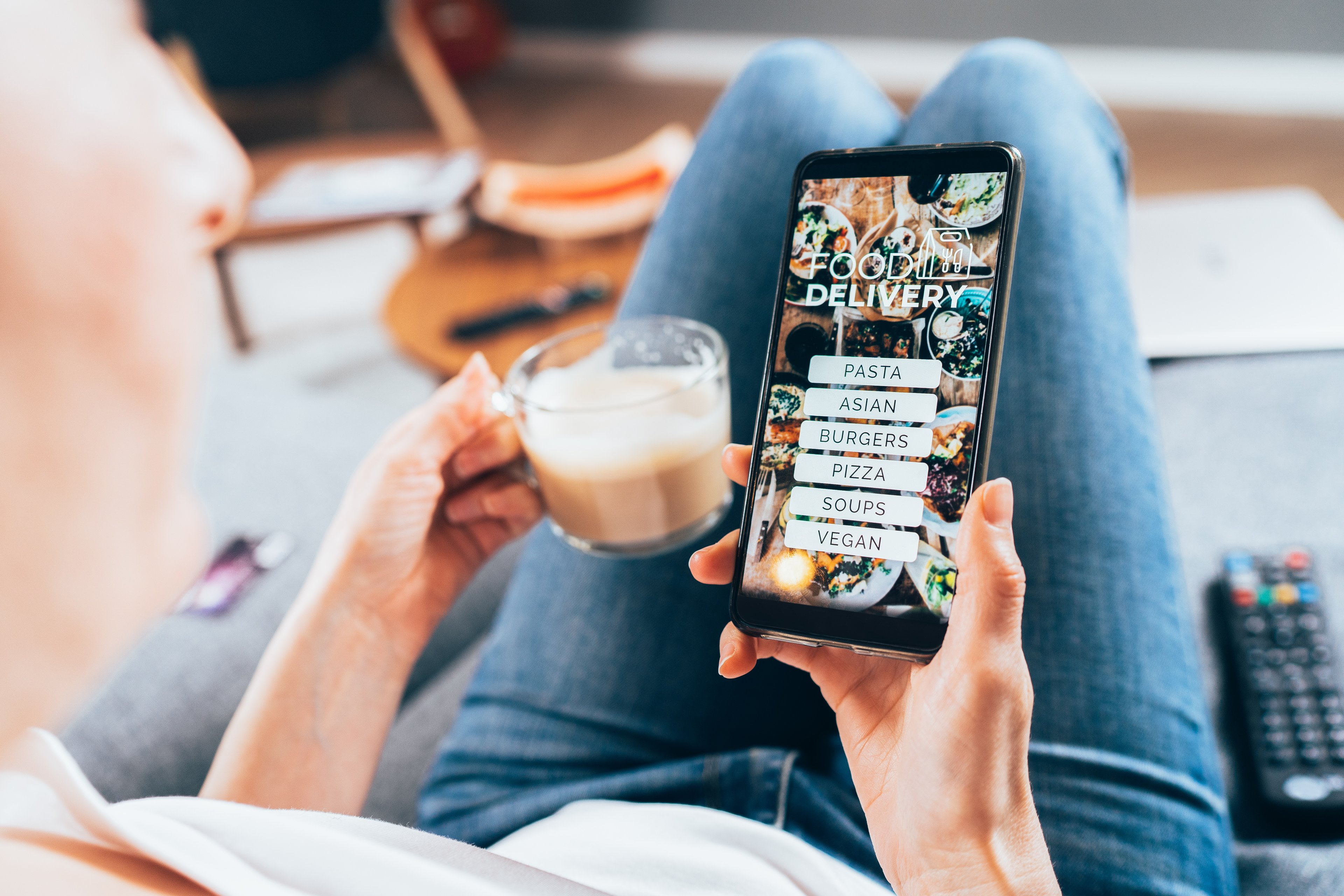 A person drinking coffee and using an iPhone. 