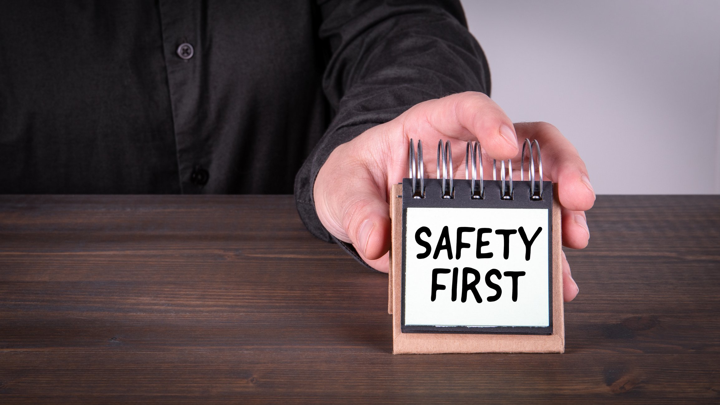 A businessman places a small sign on a table, reading Safety First.